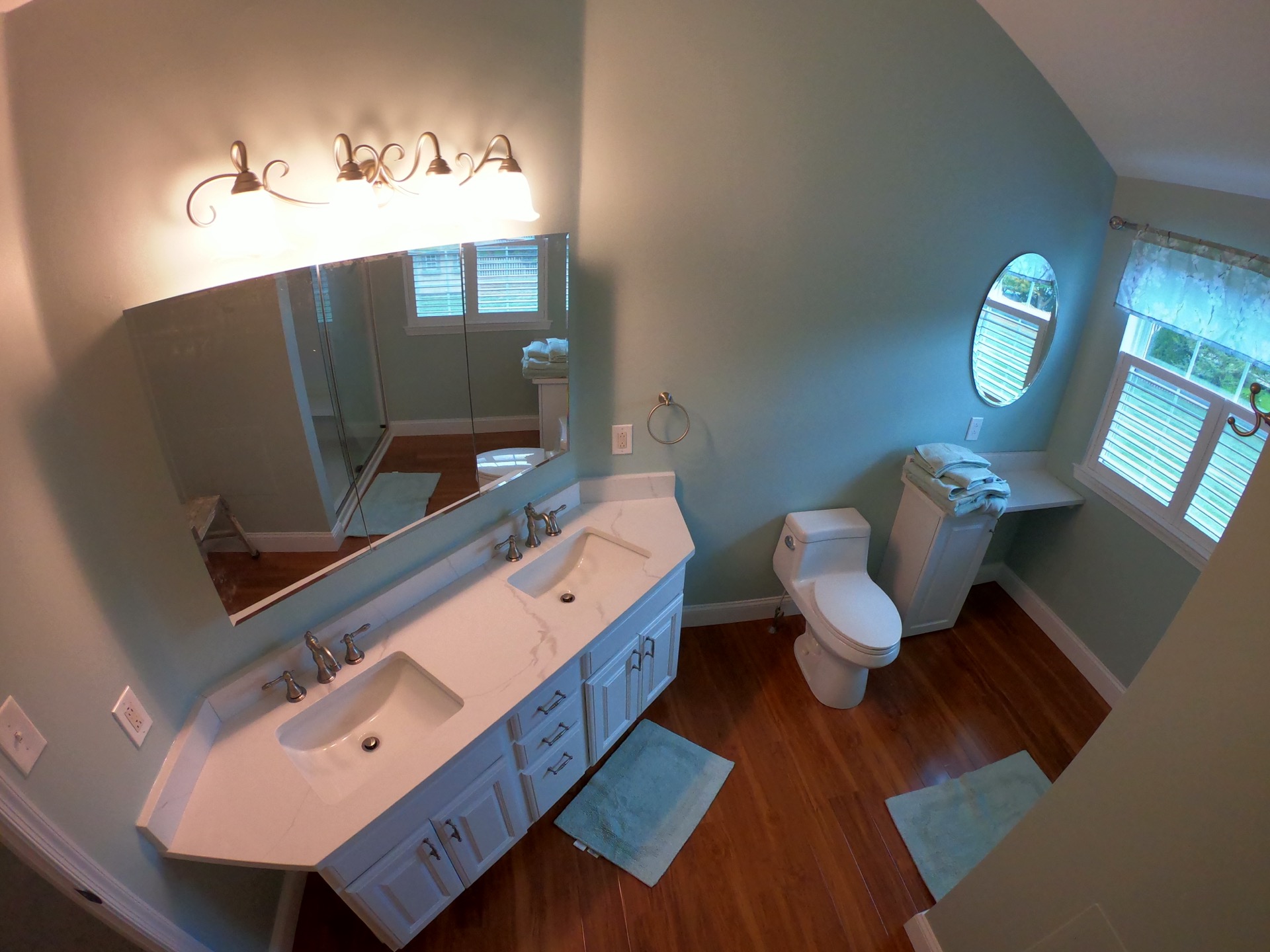 Finished bathroom with double vanity and wood floor