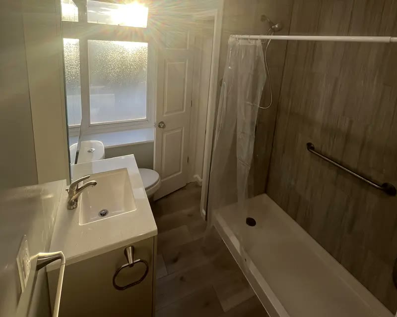 Finished bathroom with wood-look tile shower, white vanity, and wood-look floor