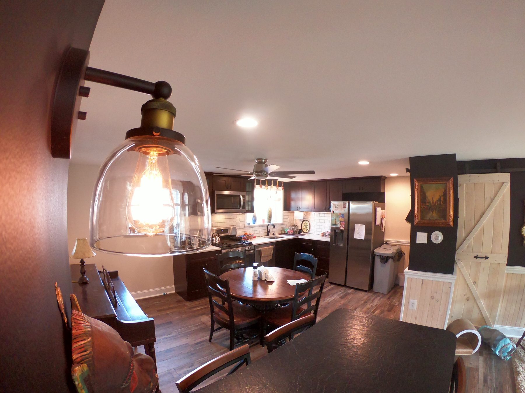 Open kitchen and dining remodel with dark cabinets, subway tile, and sliding barn door