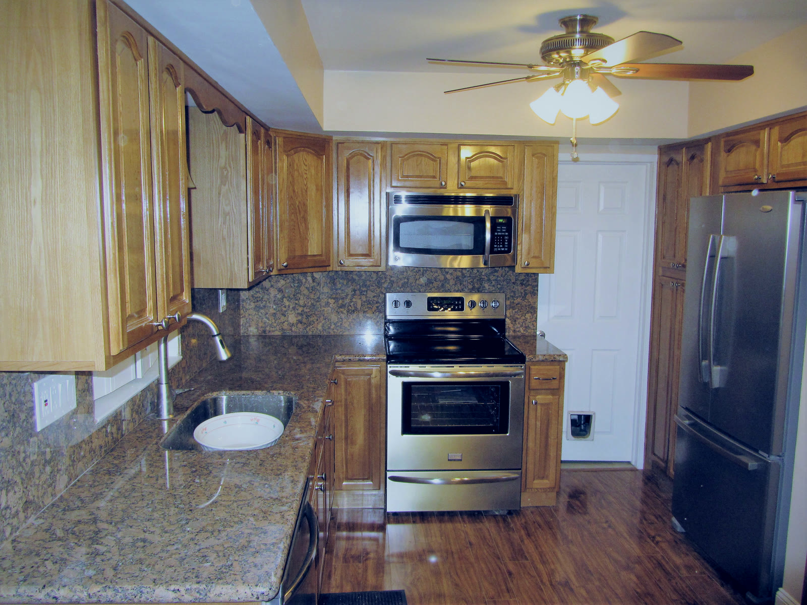 Bensalem kitchen remodel with honey-oak cabinets and full granite backsplash — The Remediation Tech